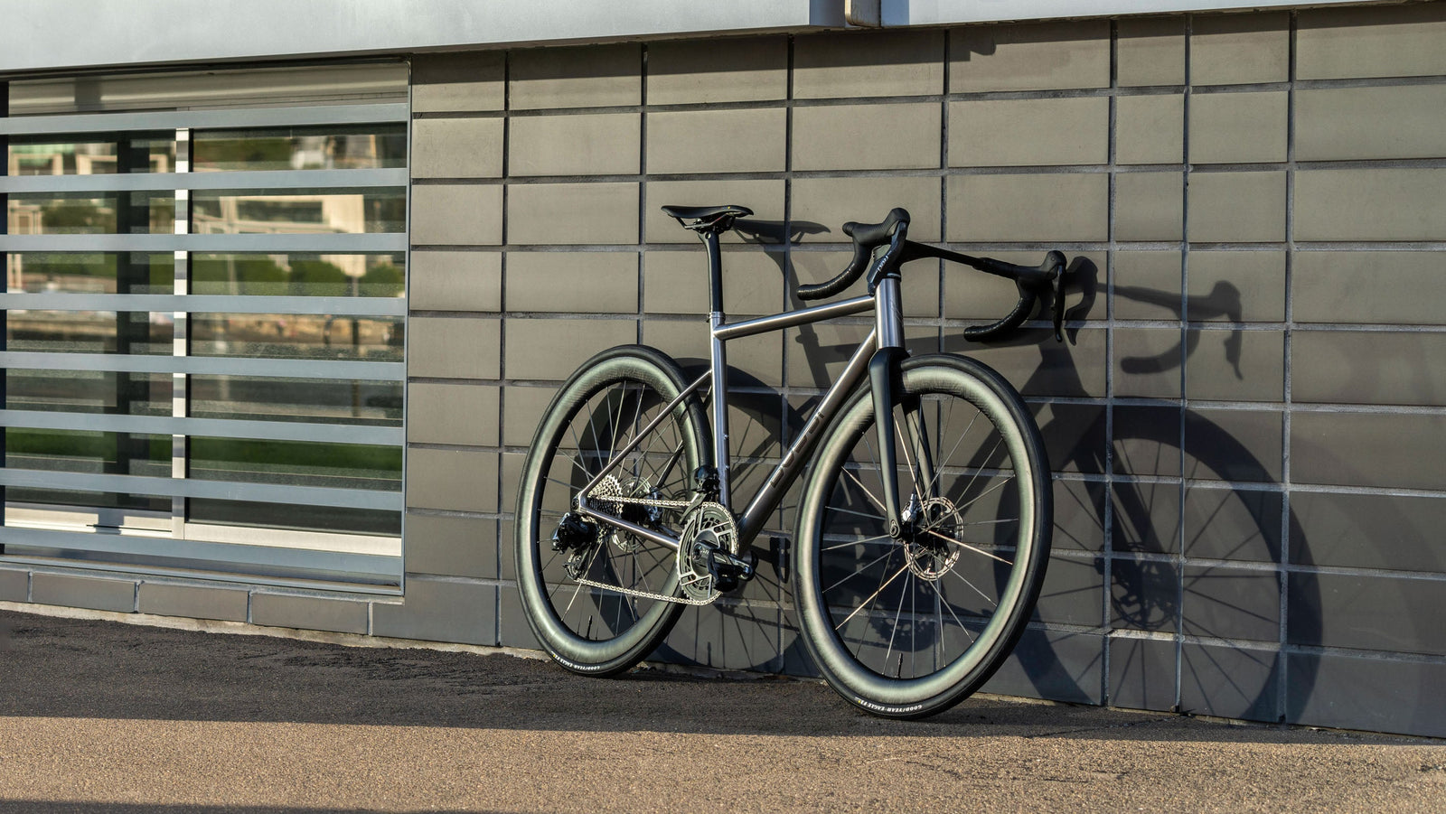 Bicycle leaning against a tiled wall with a building in the background
